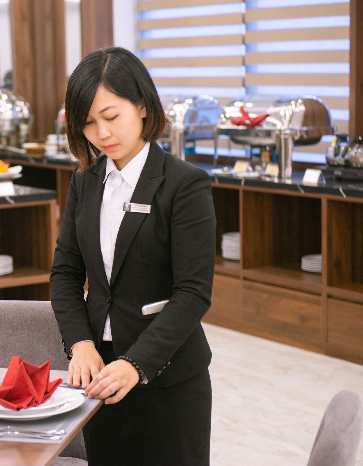 Waitress in white shirt, black half suit, and service badge